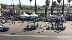Outdoor event with tents, people, vehicles, and a police car